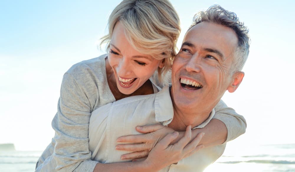 Middle aged couple on the beach smiling