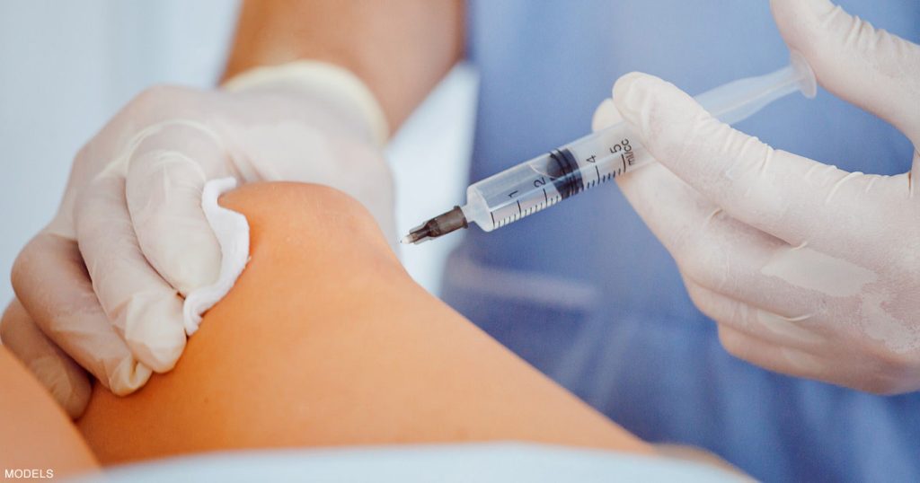 Doctor injecting treatment into patients knee