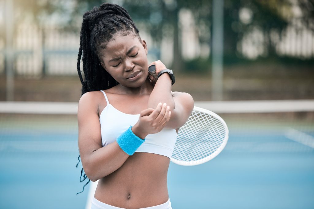 tennis player holding hurt elbow