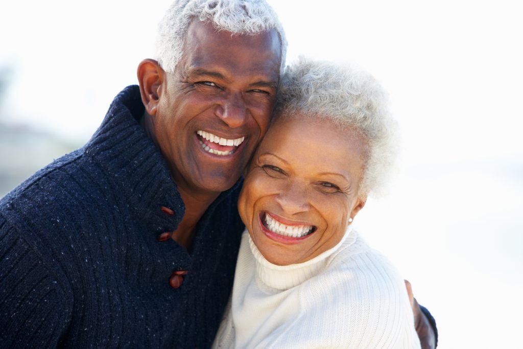Senior couple hugs, places their faces side by side as they smile at the camera.