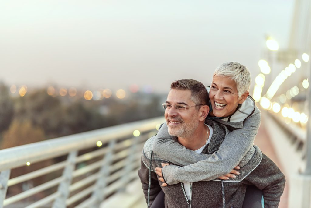 Mature couple having fun while the man gives the woman a piggy-back ride.