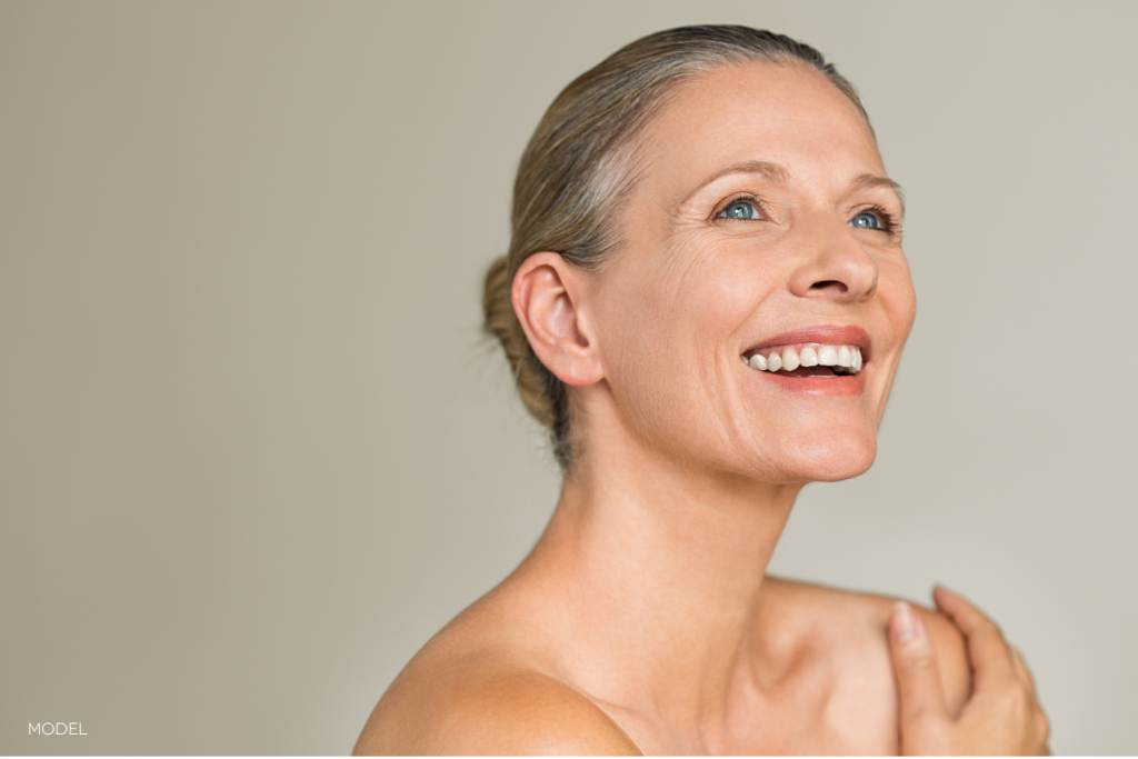 middle-aged woman, happy and smiling, looking upwards, with bare skin, hair pulled back