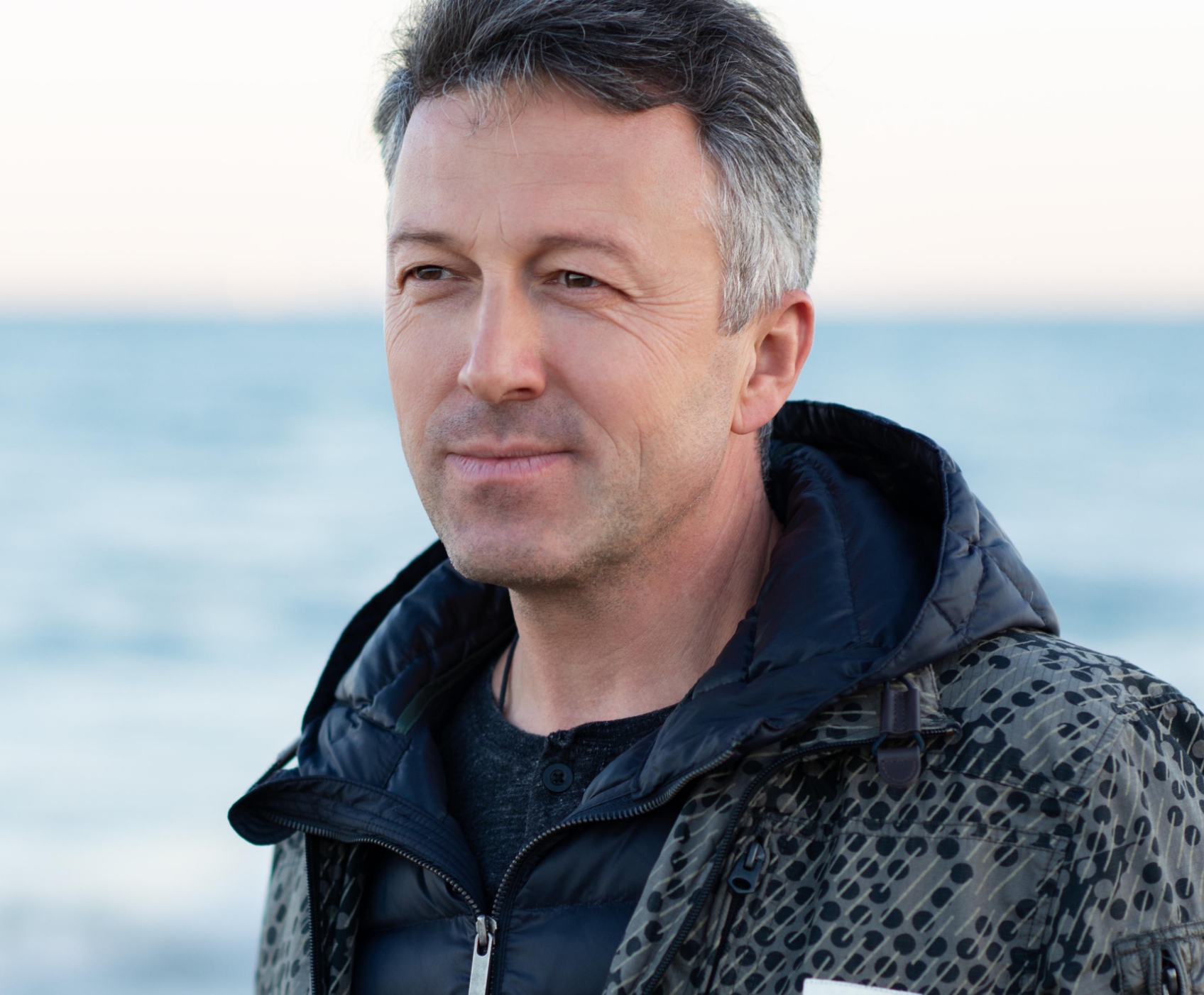 Man smiling and staring next to the ocean