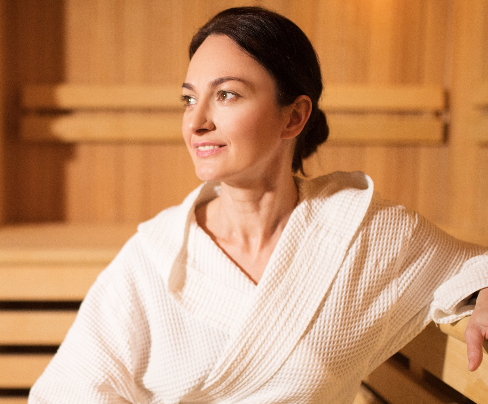 Woman sitting in the sauna wearing a robe