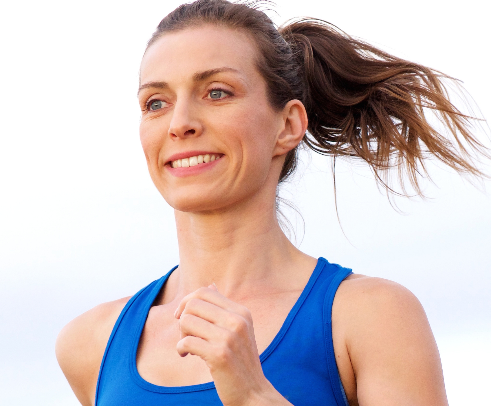 Woman smiling and running wearing a blue workout shirt