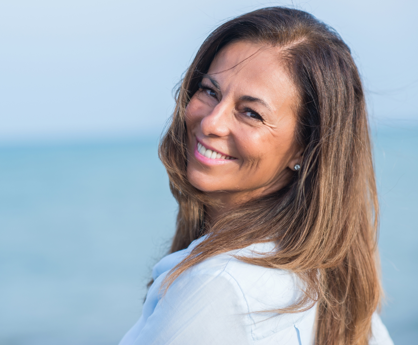 Woman turning around and smiling next to the ocean