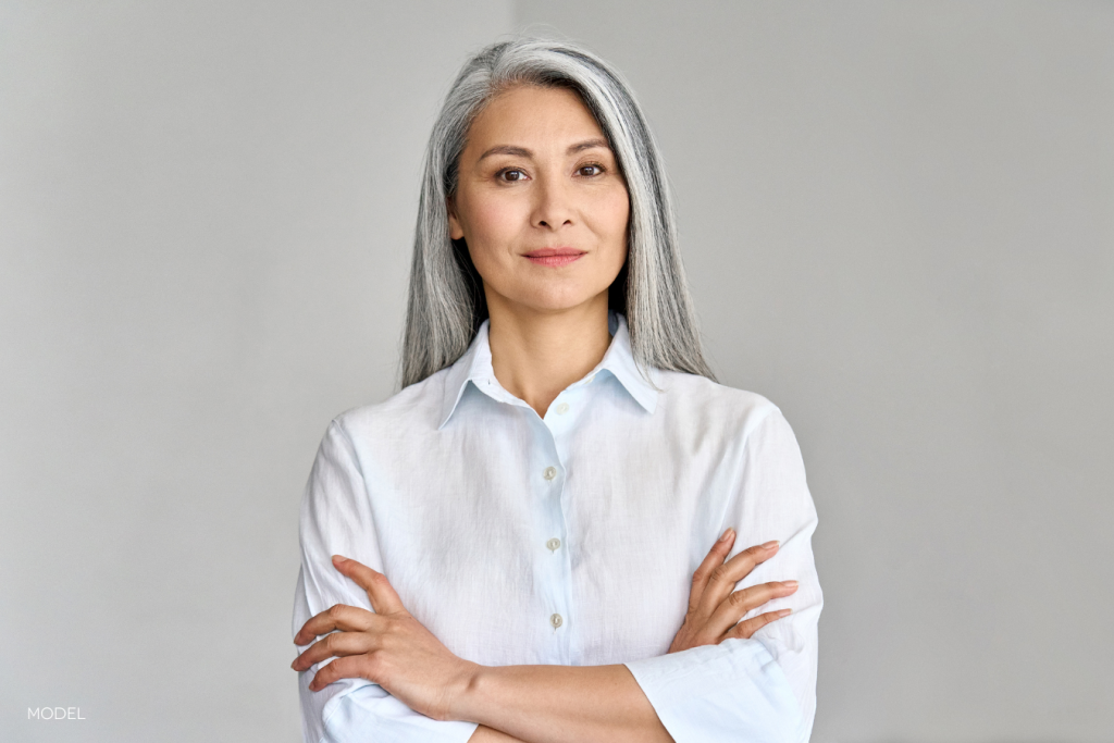 middle-aged woman looking confidently directly at the camera with her arms crossed and a slight smile on her face